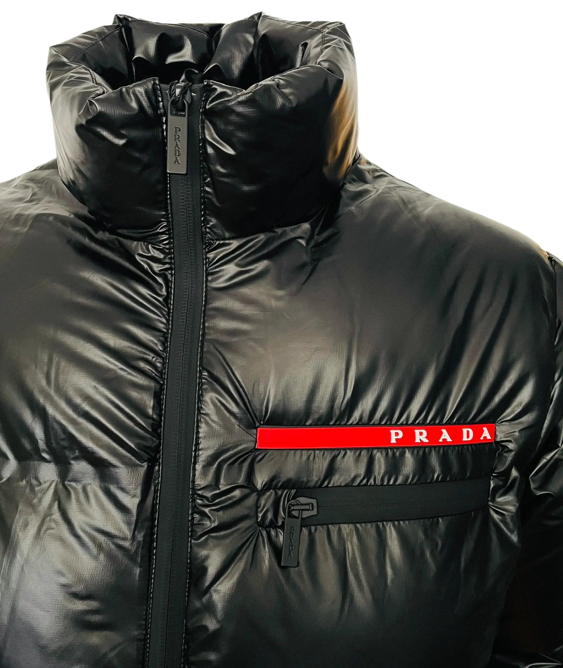 Close-up of black Prada puffer jacket with high collar and red logo patch